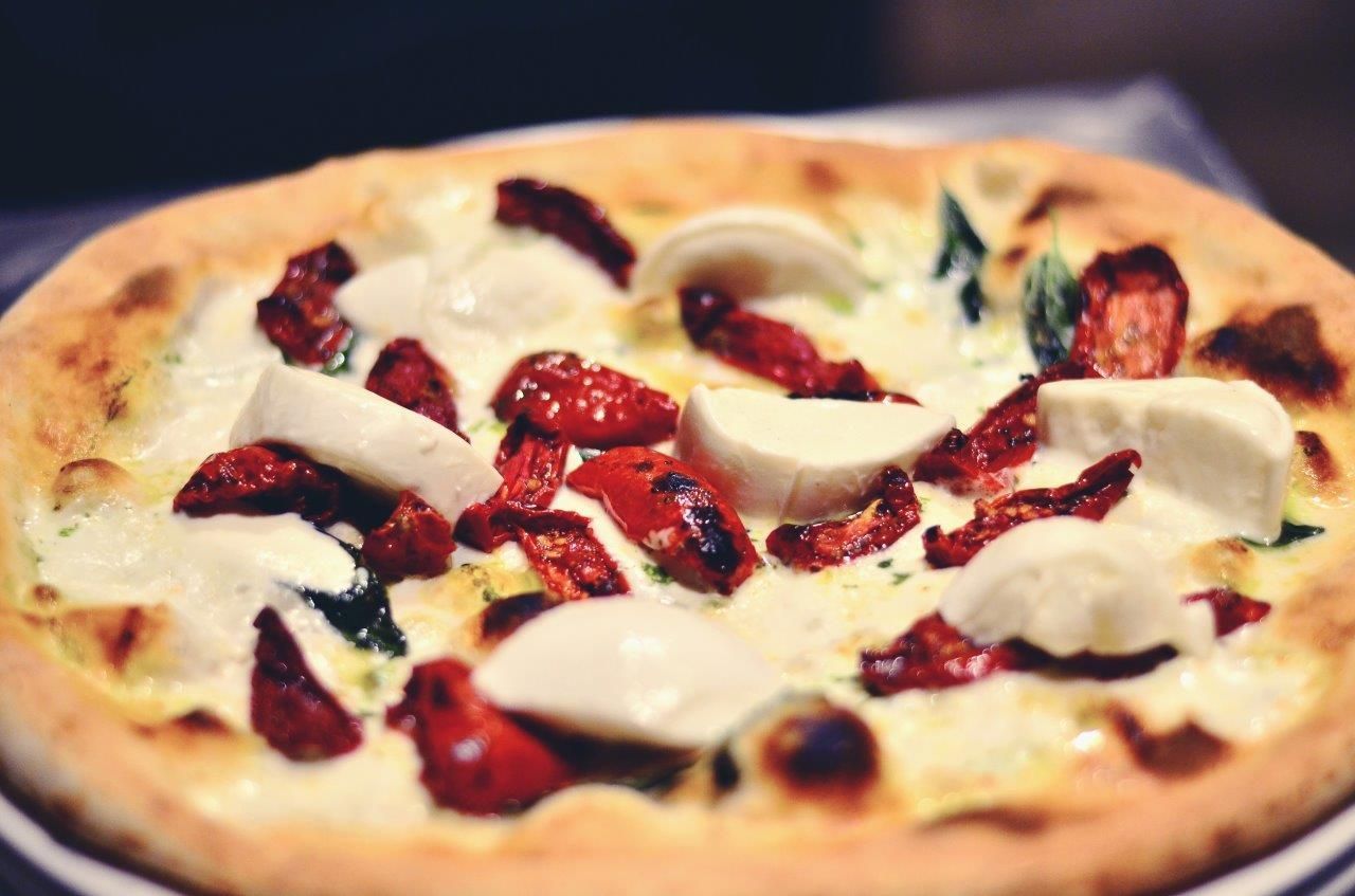 Pizza con mozzarella, pomodori secchi e basilico su un impasto.