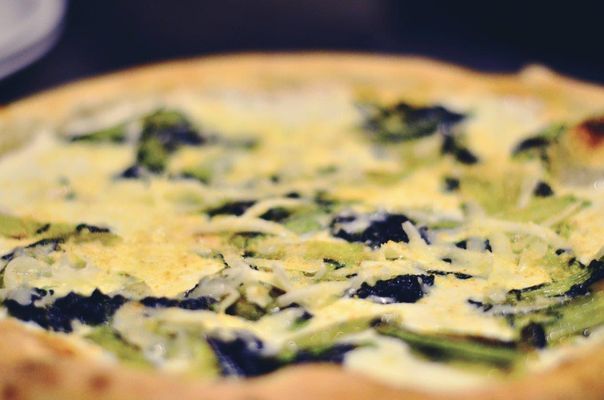 Primo piano di una quiche con verdure verdi e formaggio su una crosta dorata.