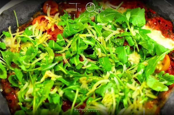 Pizza con rucola e formaggio grattugiato.