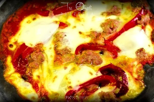 Pizza condita con peperoni rossi, formaggio e carne macinata, cotta al forno fino a ottenere una finitura dorata.