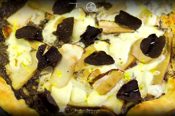 Pizza con fettine di tartufo scuro, funghi e formaggio.