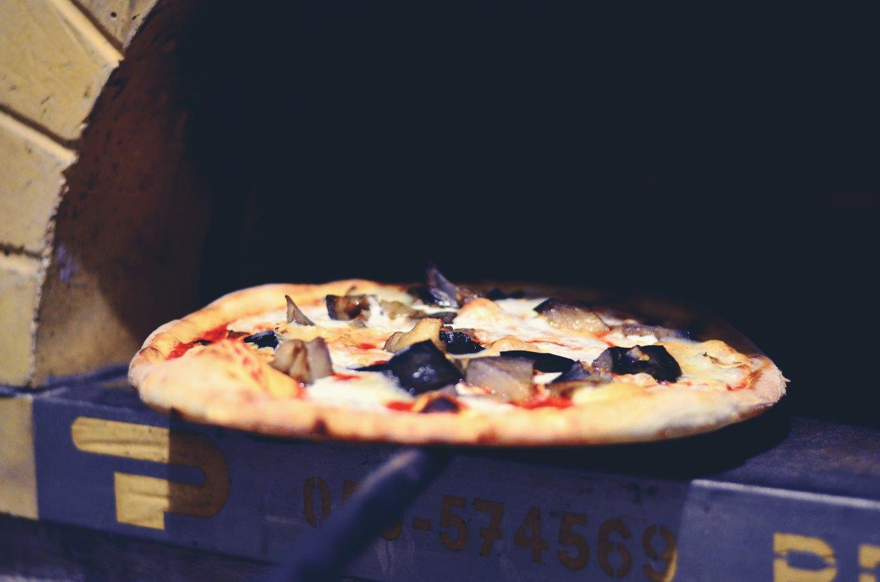 Pizza cotta nel forno a legna, con ingredienti a vista.