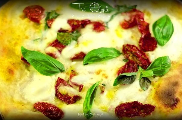 Pizza condita con formaggio bianco, pomodori secchi e basilico fresco.