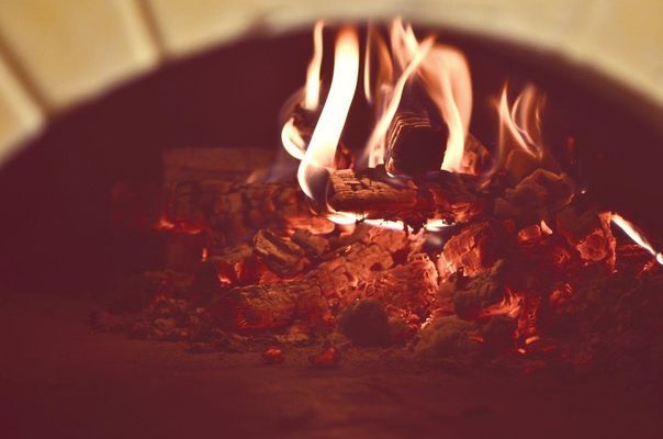 Legna da ardere bruciata in un forno di mattoni, con fiamme e braci ardenti.