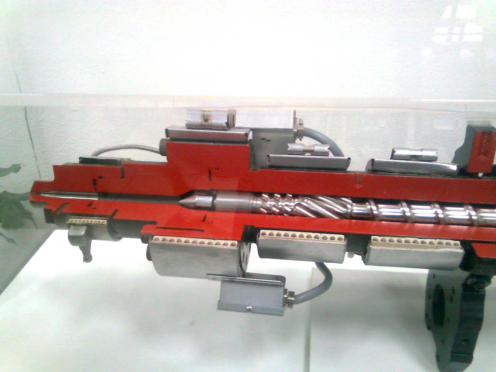 Un rifle de juguete rojo y negro se exhibe en una vitrina sobre un fondo blanco.