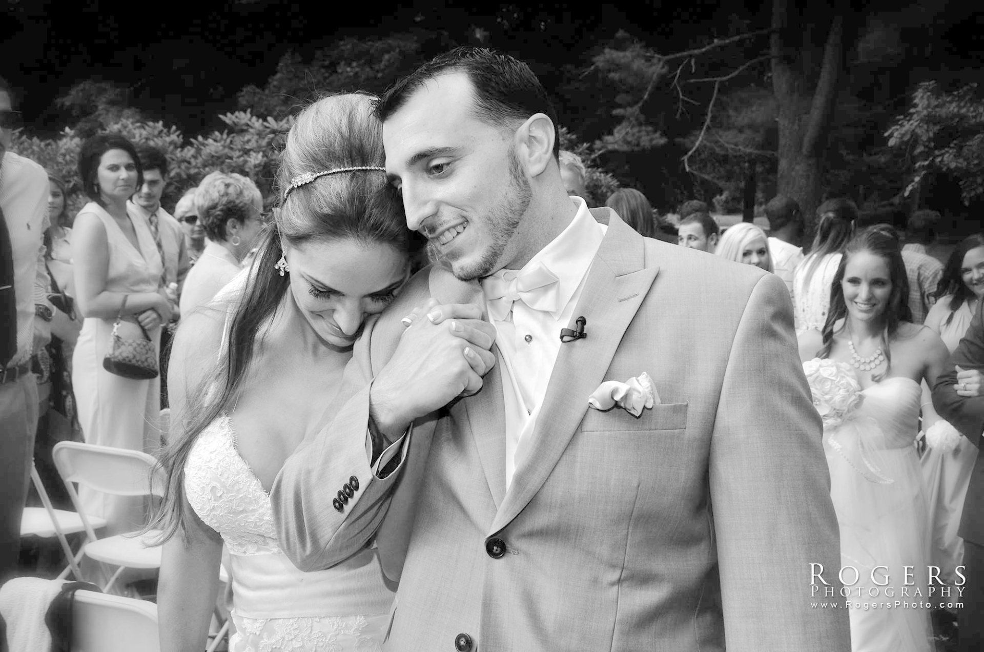A black and white photo of a bride and groom holding hands at their wedding photographed by Rogers Photography in Connecticut. 
