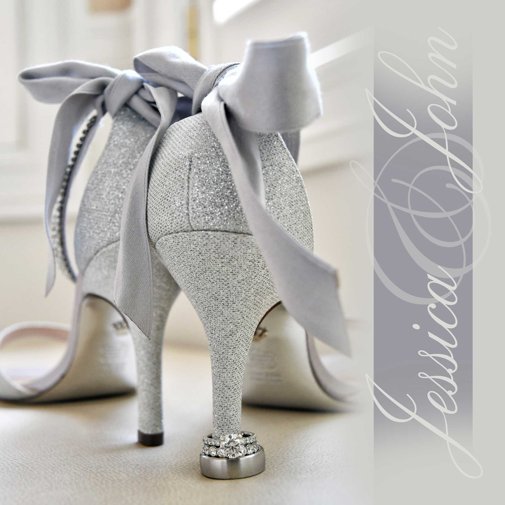 Sparkly silver high-heeled wedding shoes with bows and pearl ankle straps on a soft neutral surface.