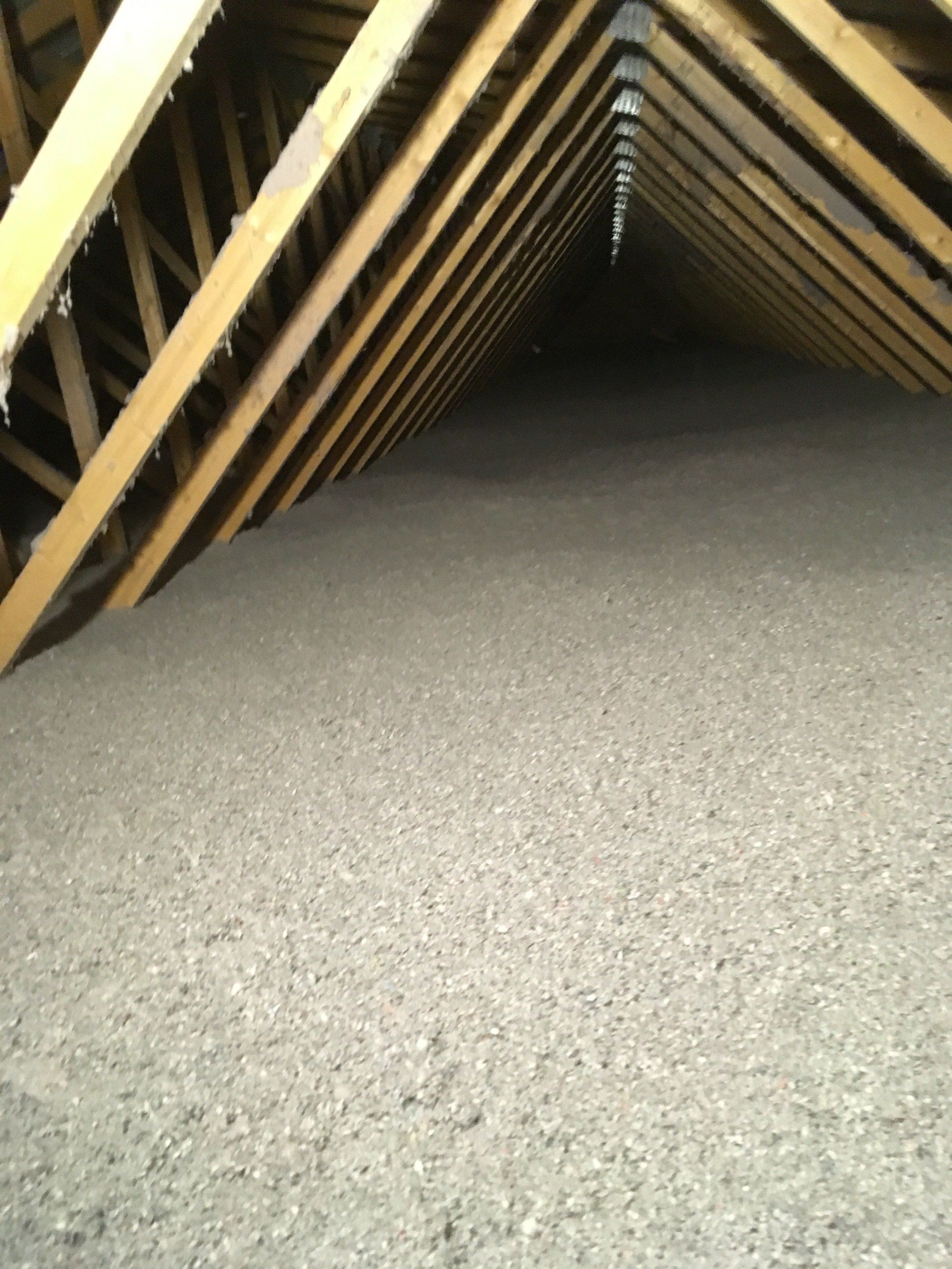 An attic with a lot of insulation and wooden beams