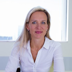 Una donna in camicia bianca è seduta davanti a una finestra.