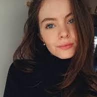 Un primo piano del volto di una donna che indossa un dolcevita nero e orecchini.