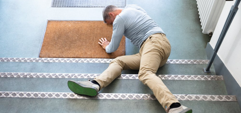 Mature Man Lying On Staircase After Slip And Fall Accident