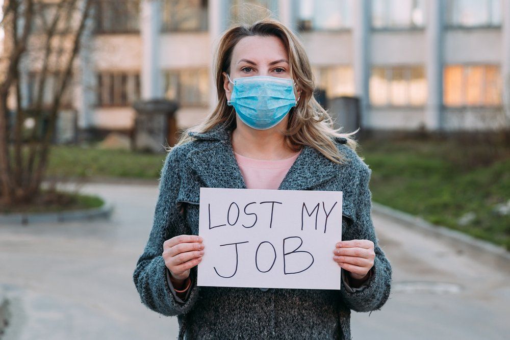 Woman in mask holds sign lost my job.