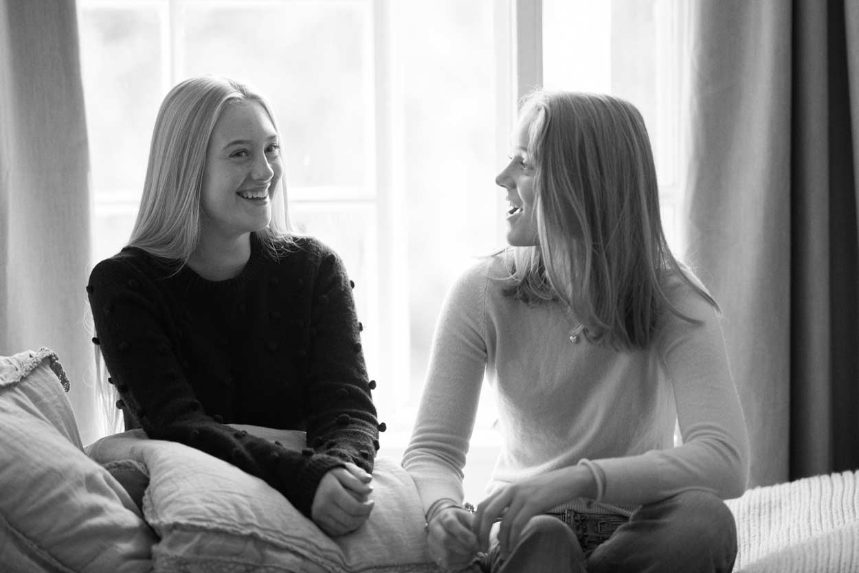 Två kvinnor sitter i en soffa och pratar med varandra.