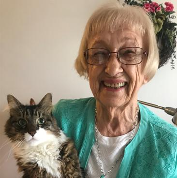 elderly woman smiling and holding her cat woman posing with her fluffy cat