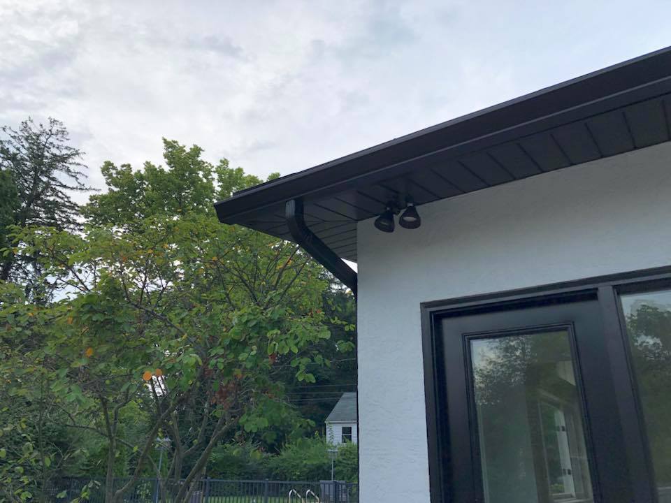 A white house with a black window and a black gutter.