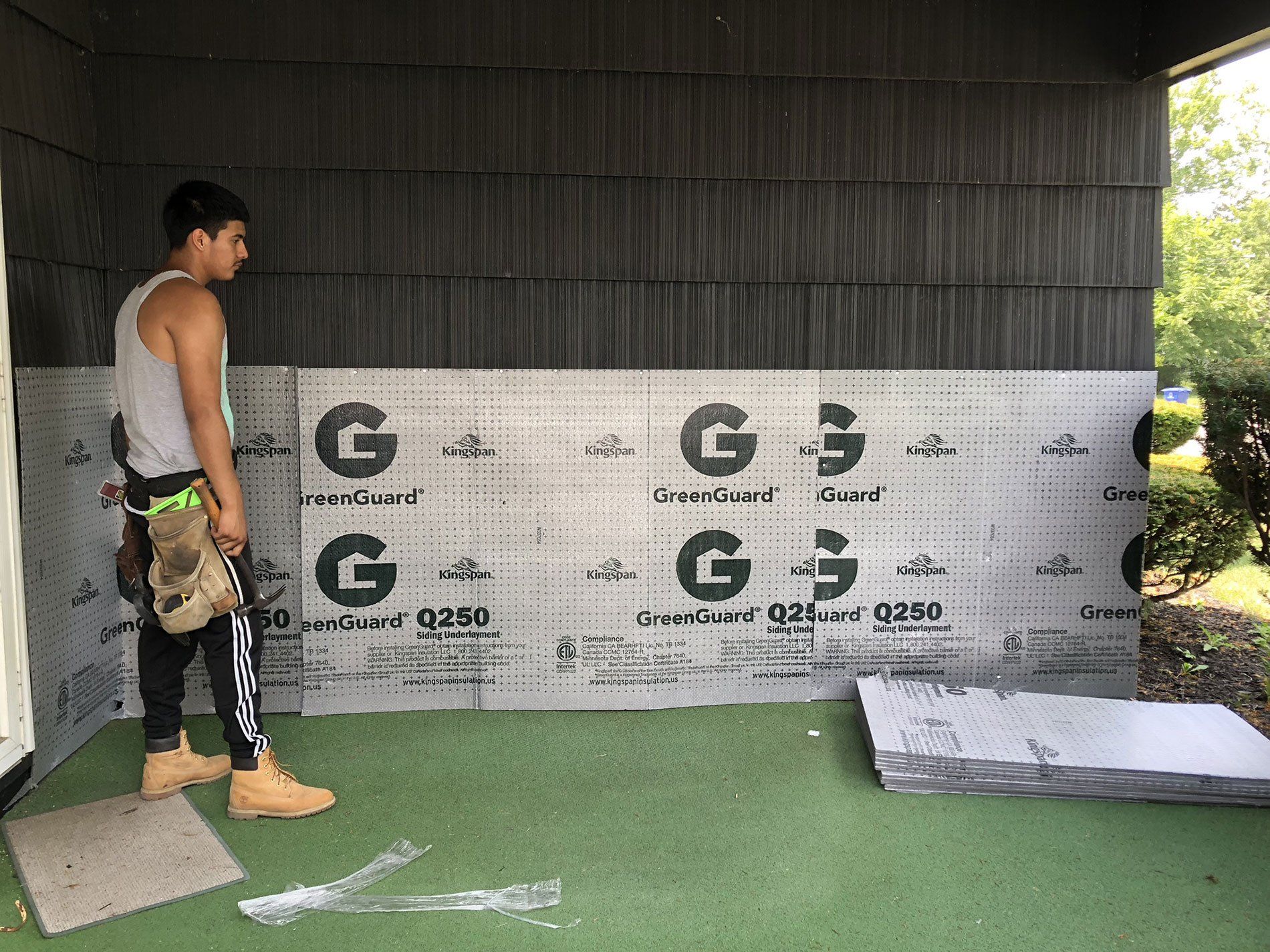 A man is standing in front of a wall with a piece of insulation on it.