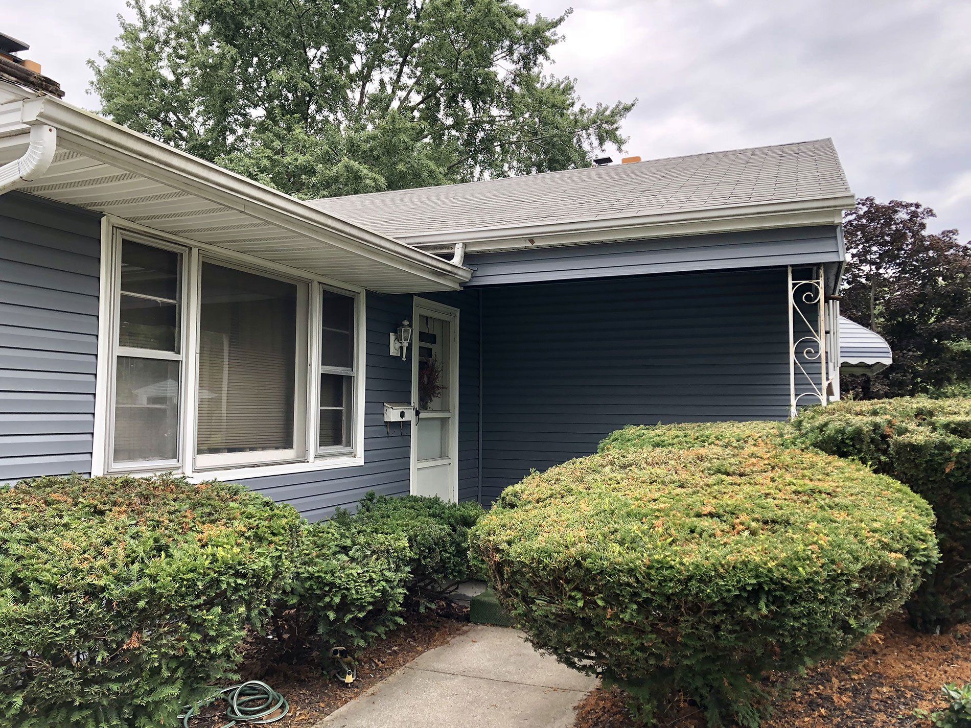 A blue house with a white door and a walkway leading to it.