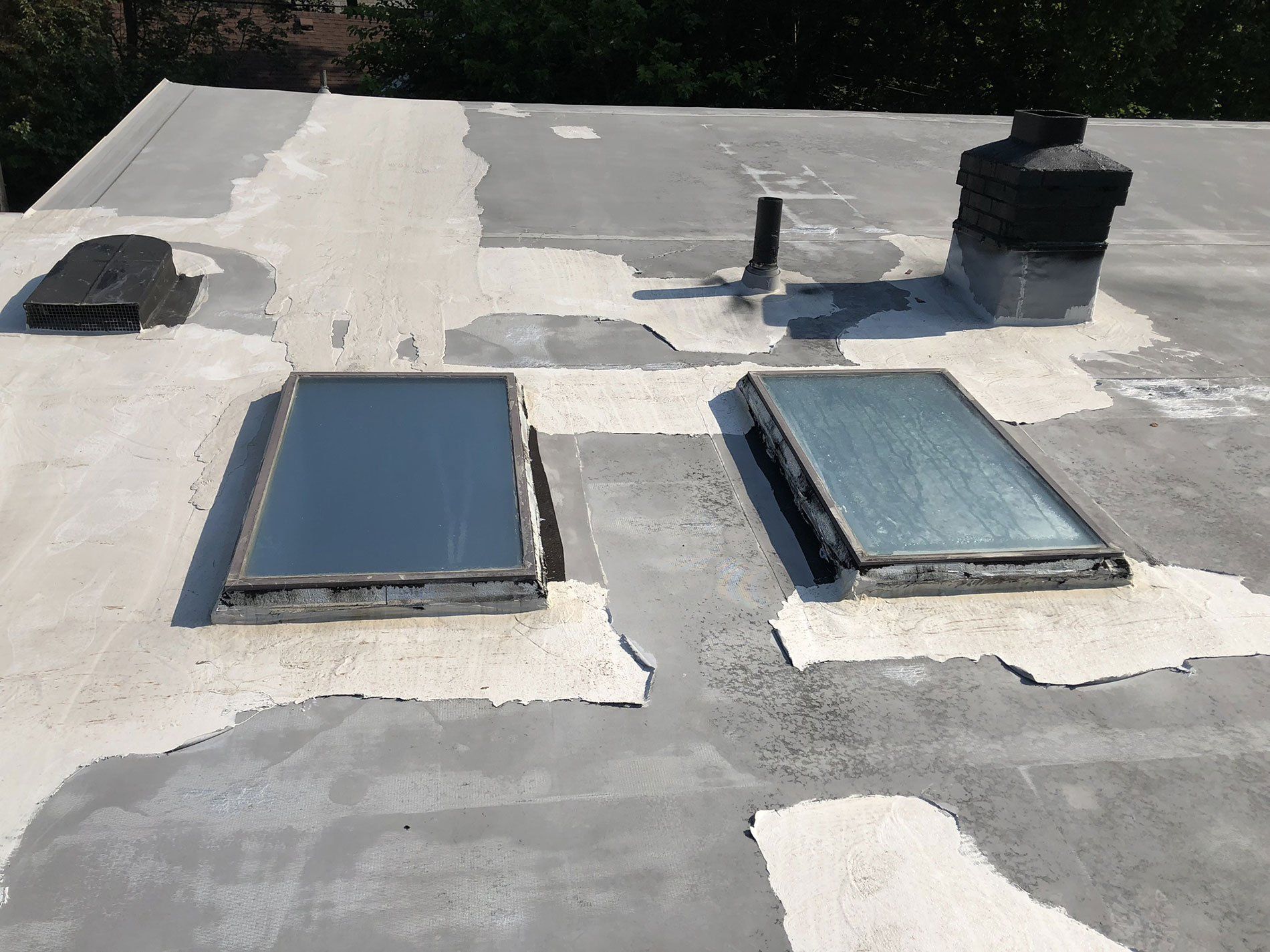 A roof with two skylights and a chimney on it