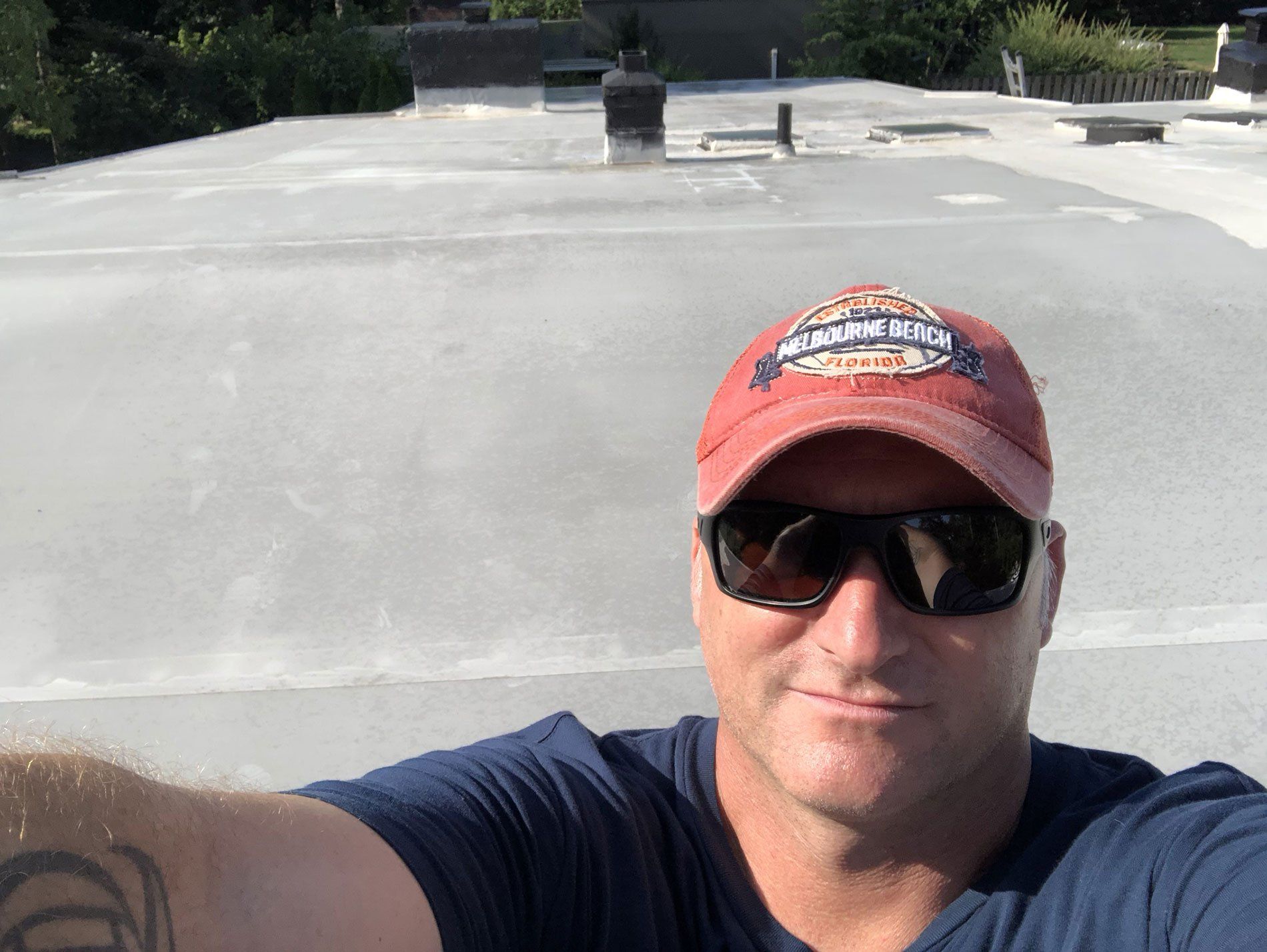 A man wearing a red hat and sunglasses is taking a selfie.