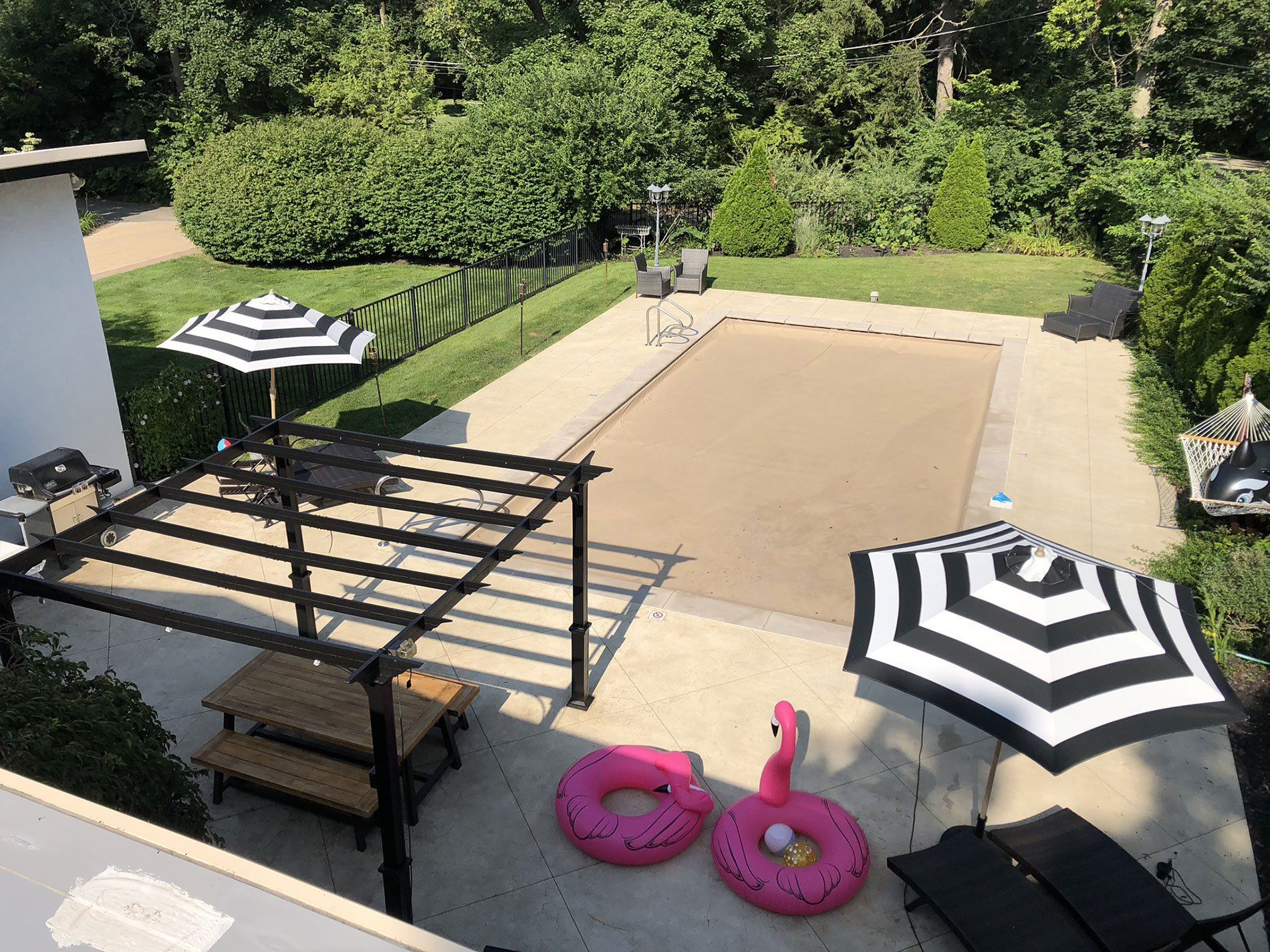 An aerial view of a backyard with a swimming pool , flamingo floats , and umbrellas.