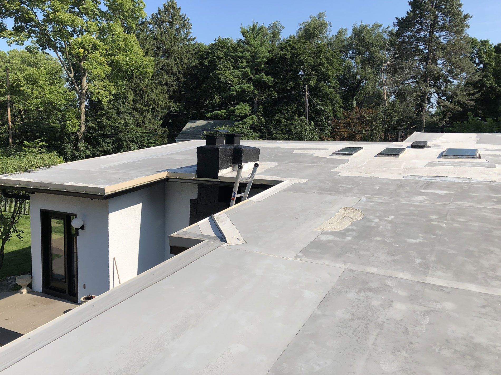 A roof of a house with a chimney on it and trees in the background.