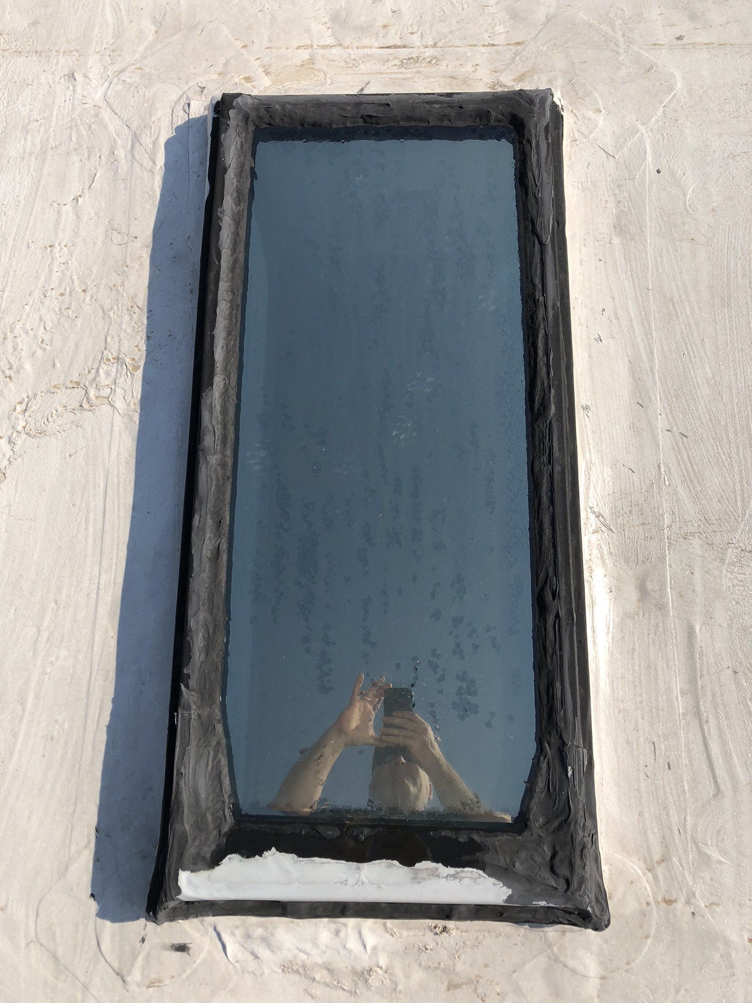 A person is taking a picture of their reflection in a window.