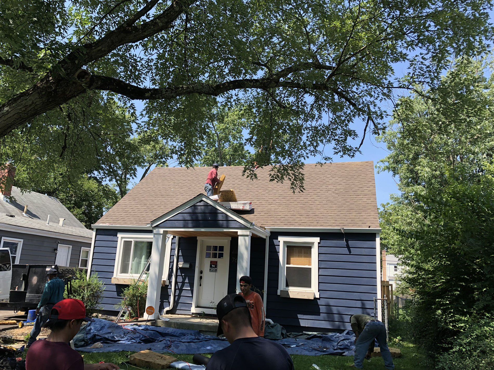 A group of people are working on the roof of a blue house.