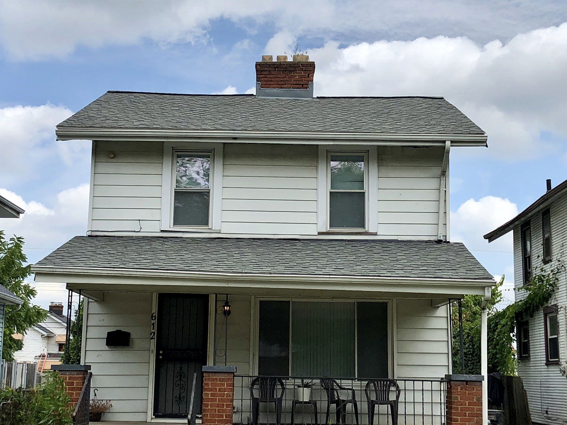 A white house with a porch and chairs in front of it