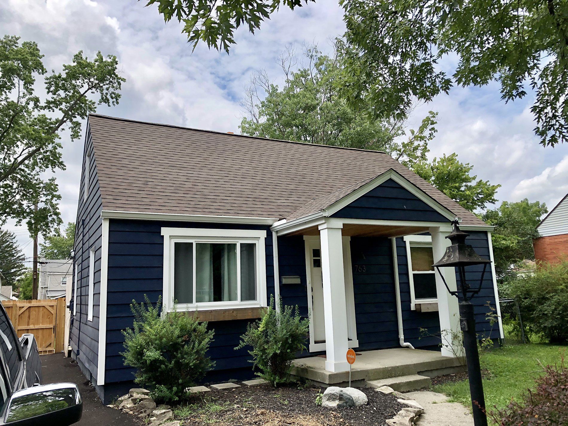 A small blue house with a car parked in front of it.