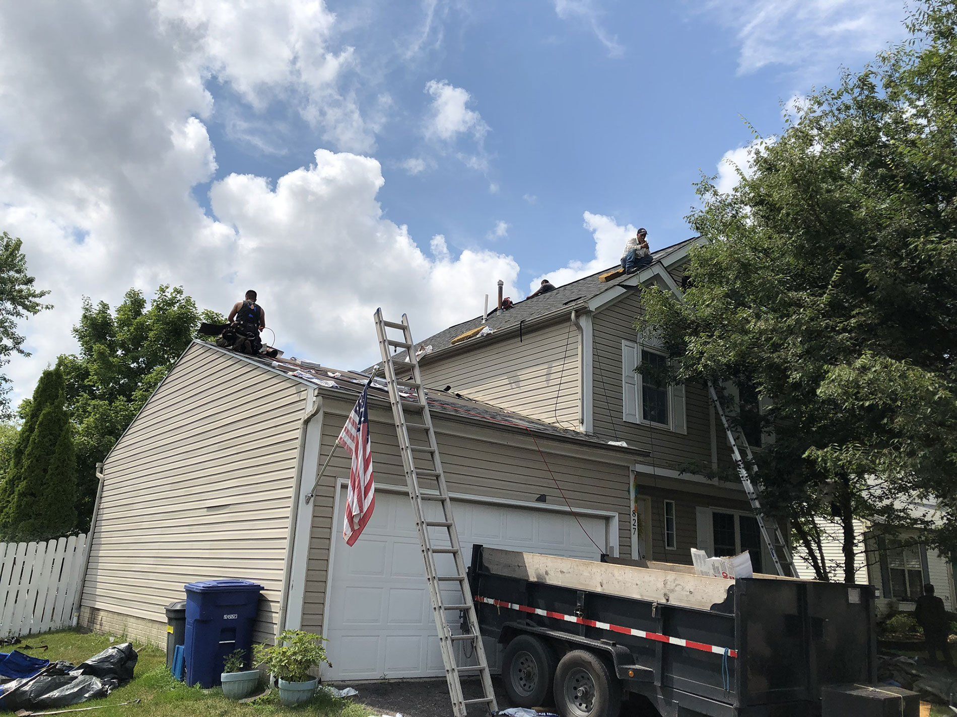 A man on a ladder is working on the roof of a house.