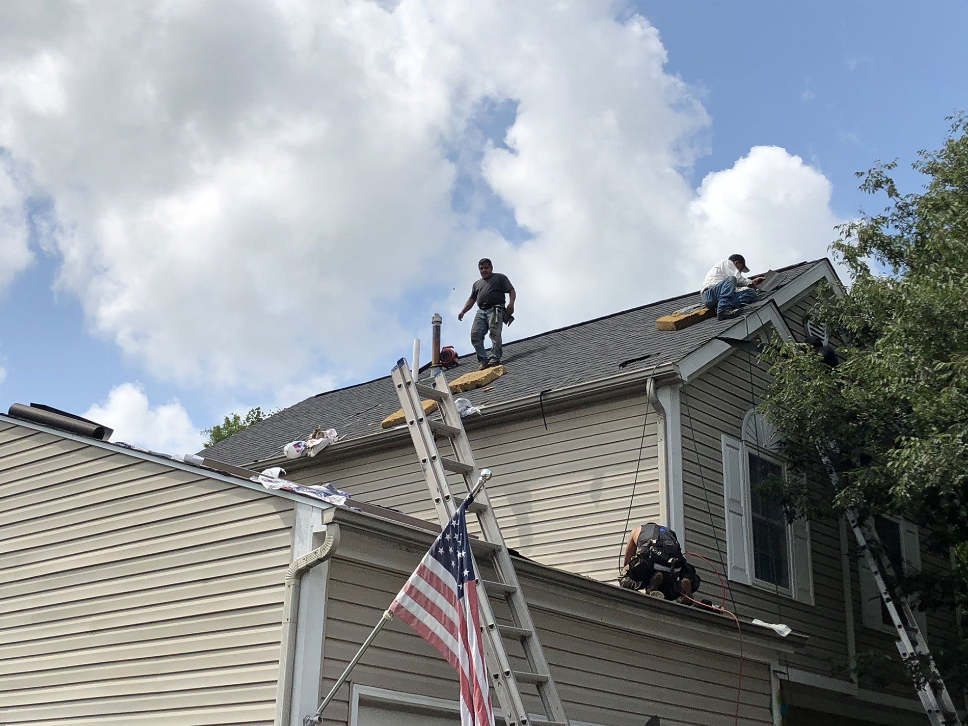 A group of men are working on the roof of a house.