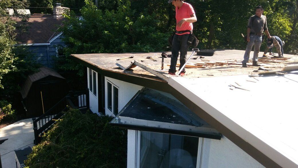 Two men are working on the roof of a house