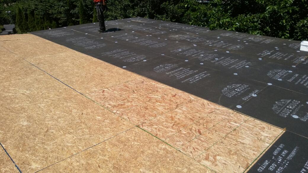 A large piece of plywood is sitting on top of a roof.