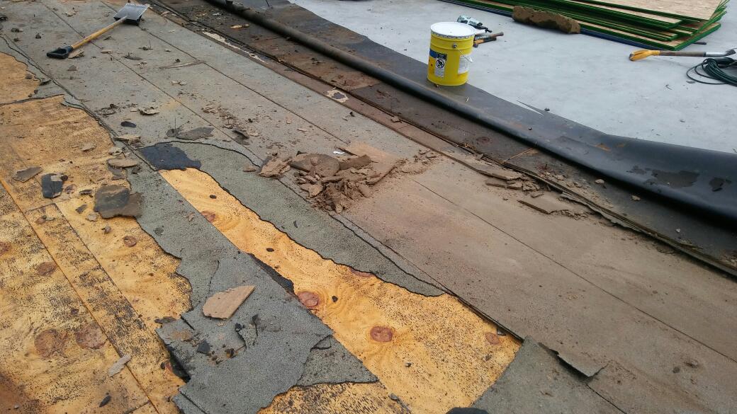 A roof with a lot of pieces of wood and a yellow container on it.