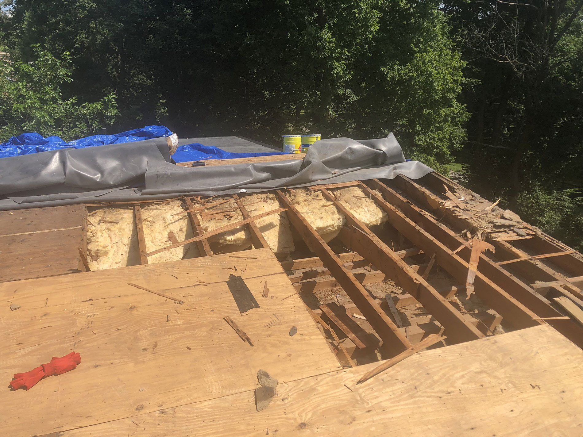 The roof of a house is being demolished and a blue tarp is covering it.