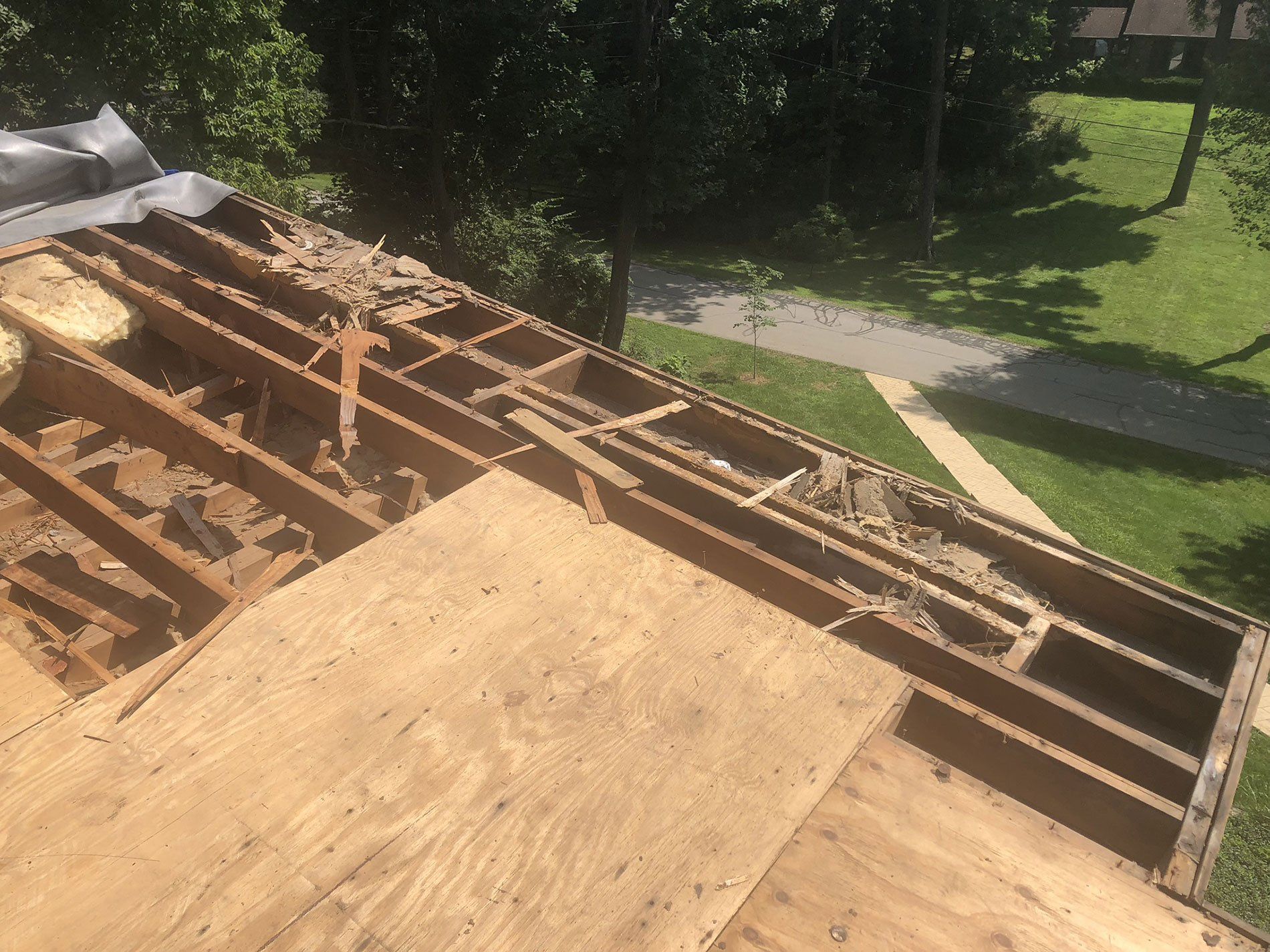The roof of a house is being removed and a wooden deck is being built on top of it.