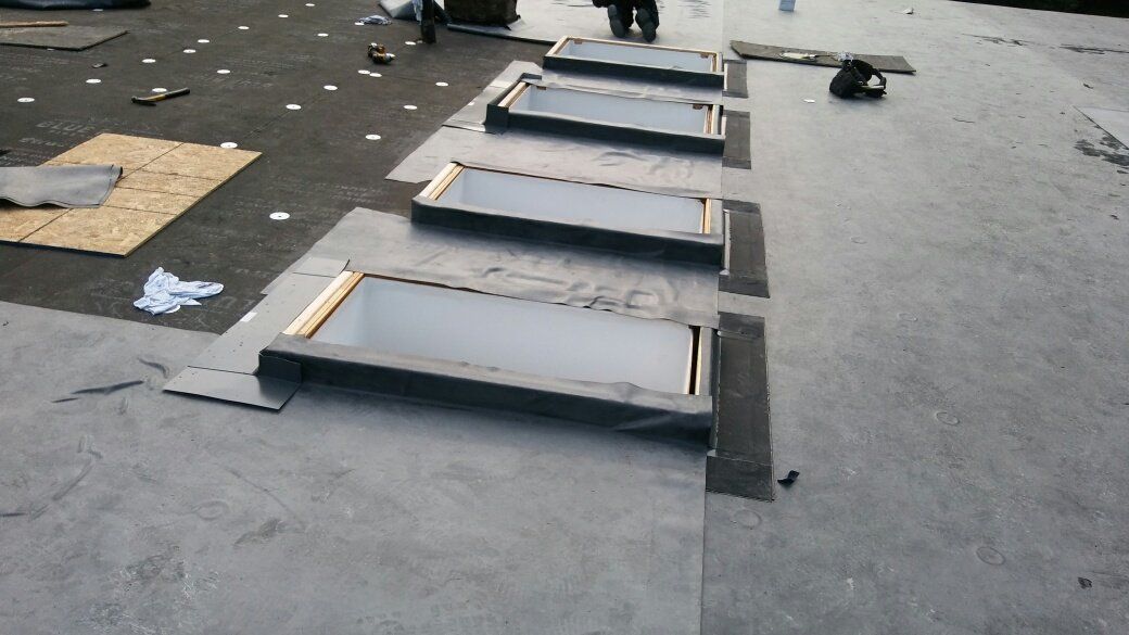 A row of skylights are being installed on a roof