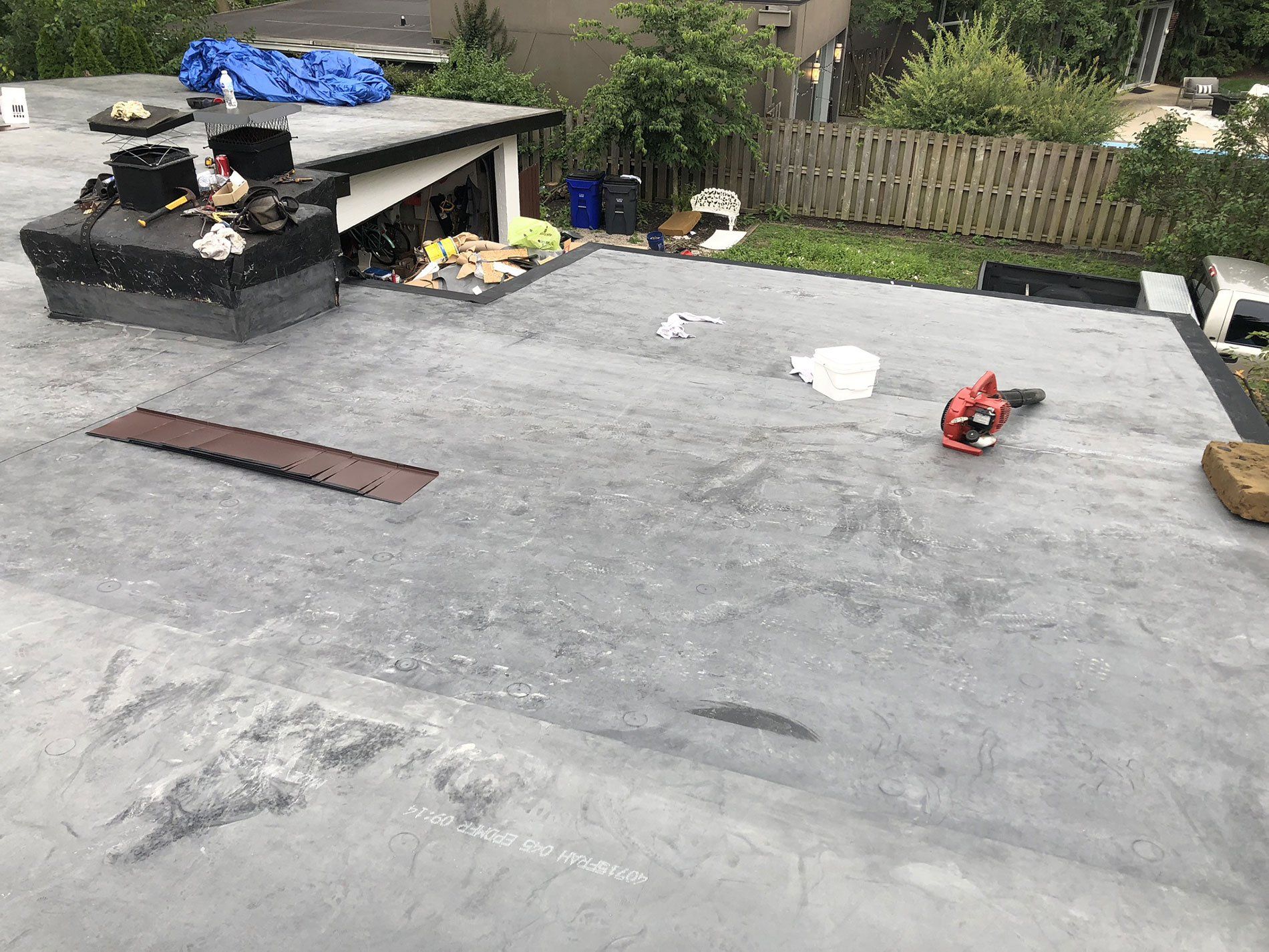 A roof with a lot of tools on it and a fence in the background.