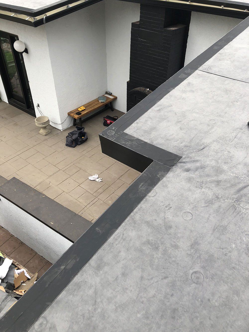 A rooftop view of a house with a patio and a bench.