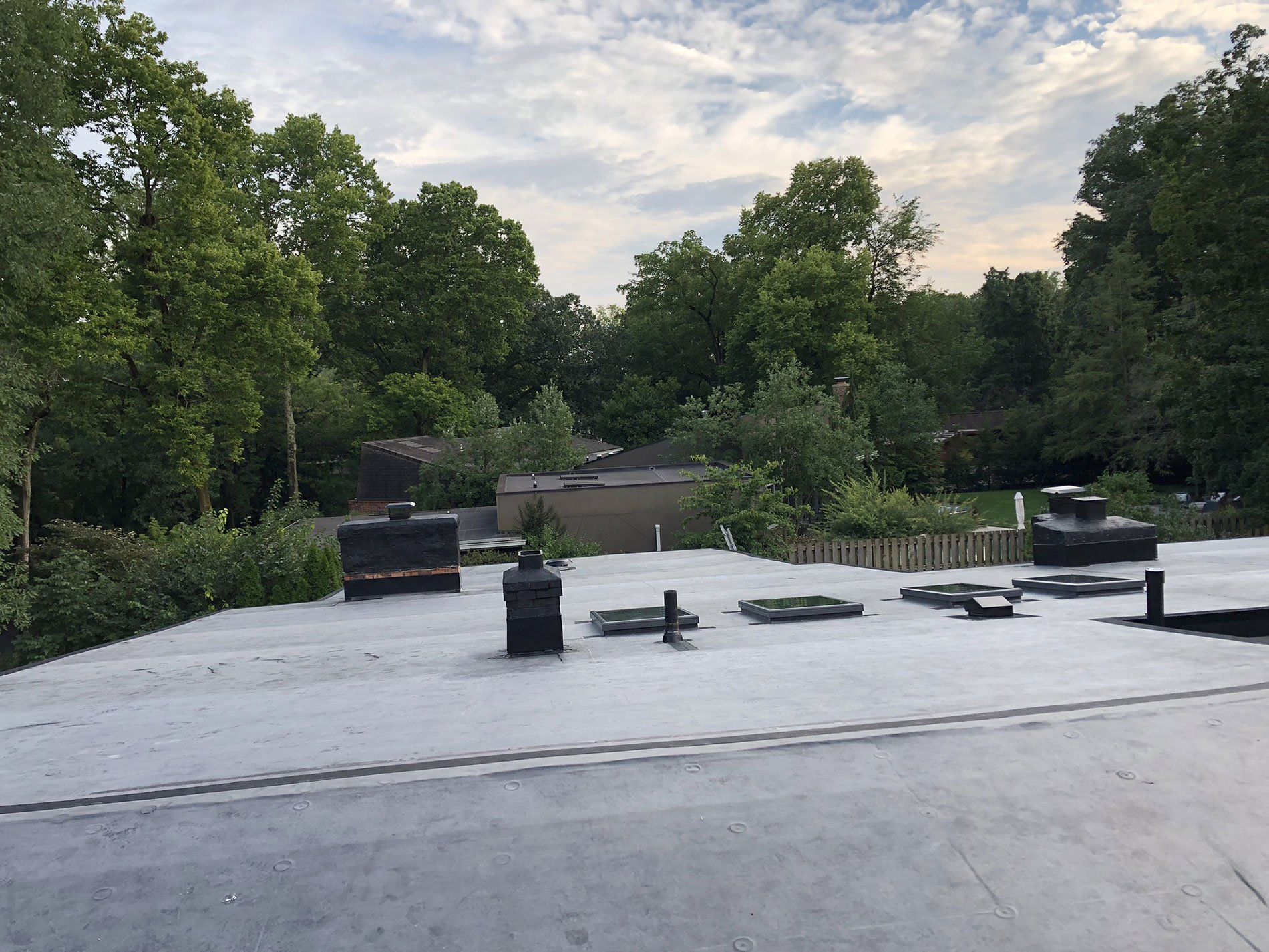 A roof with a lot of chimneys on it and trees in the background