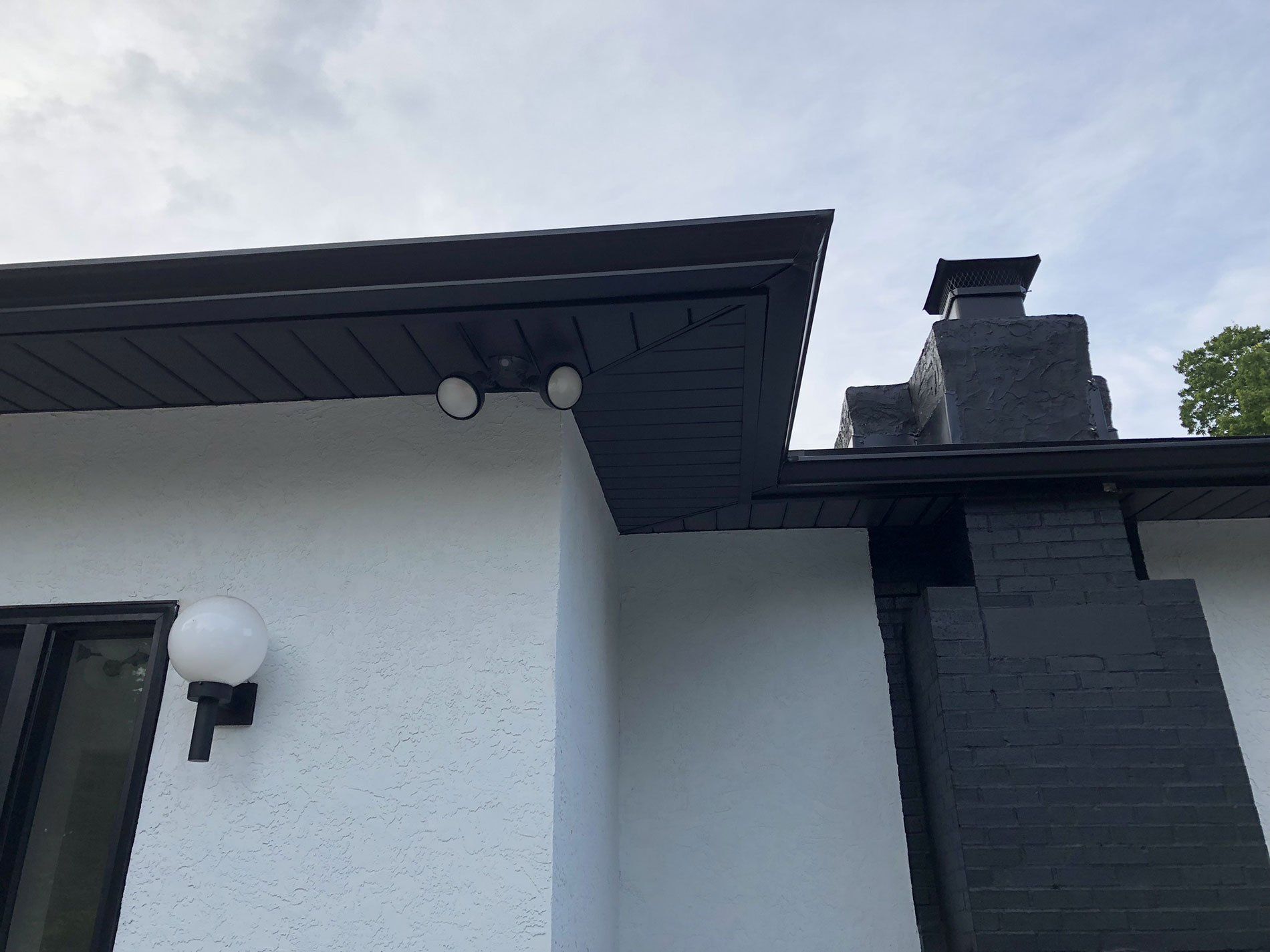 A white house with a black chimney and a light on the side.