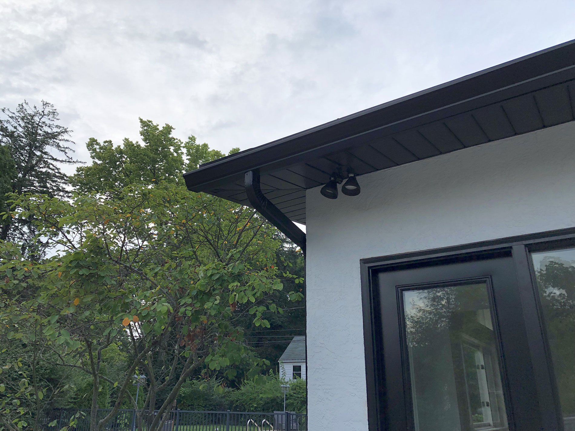 A white house with a black gutter and a black window.
