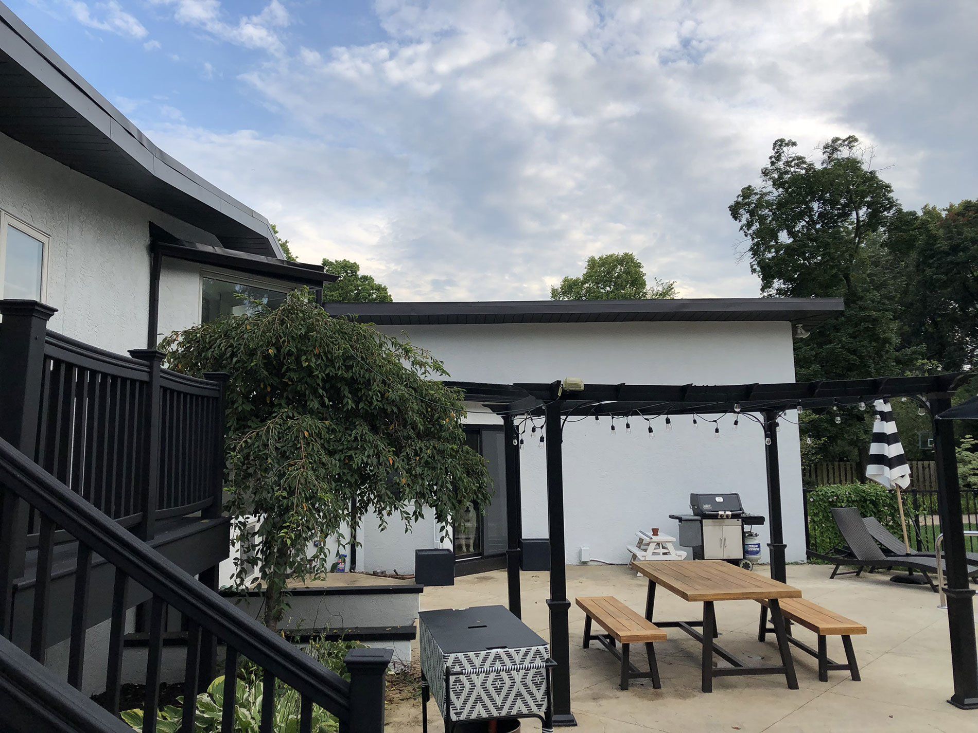 A patio with a picnic table and benches under a pergola.