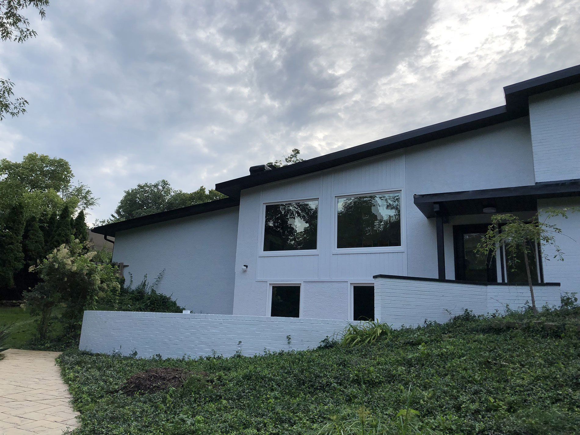 A white house with a black roof and a lot of windows
