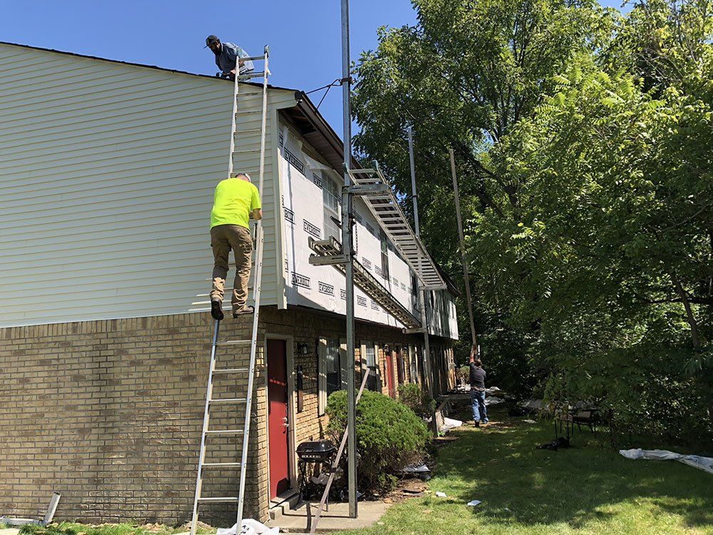 A man is standing on a ladder on the side of a building.