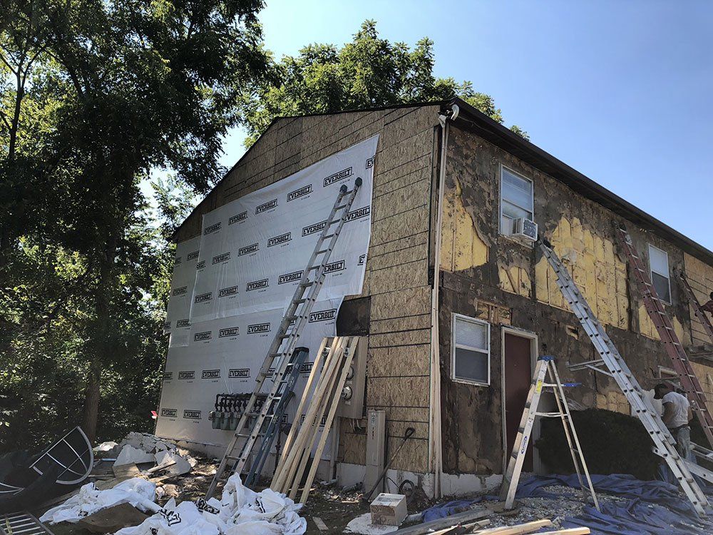 A house is being remodeled with ladders on the side of it.
