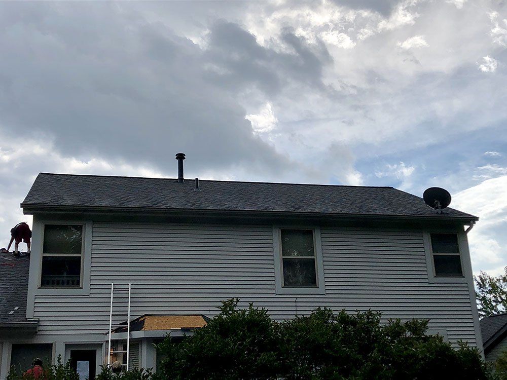 A white house with a gray roof is being remodeled.