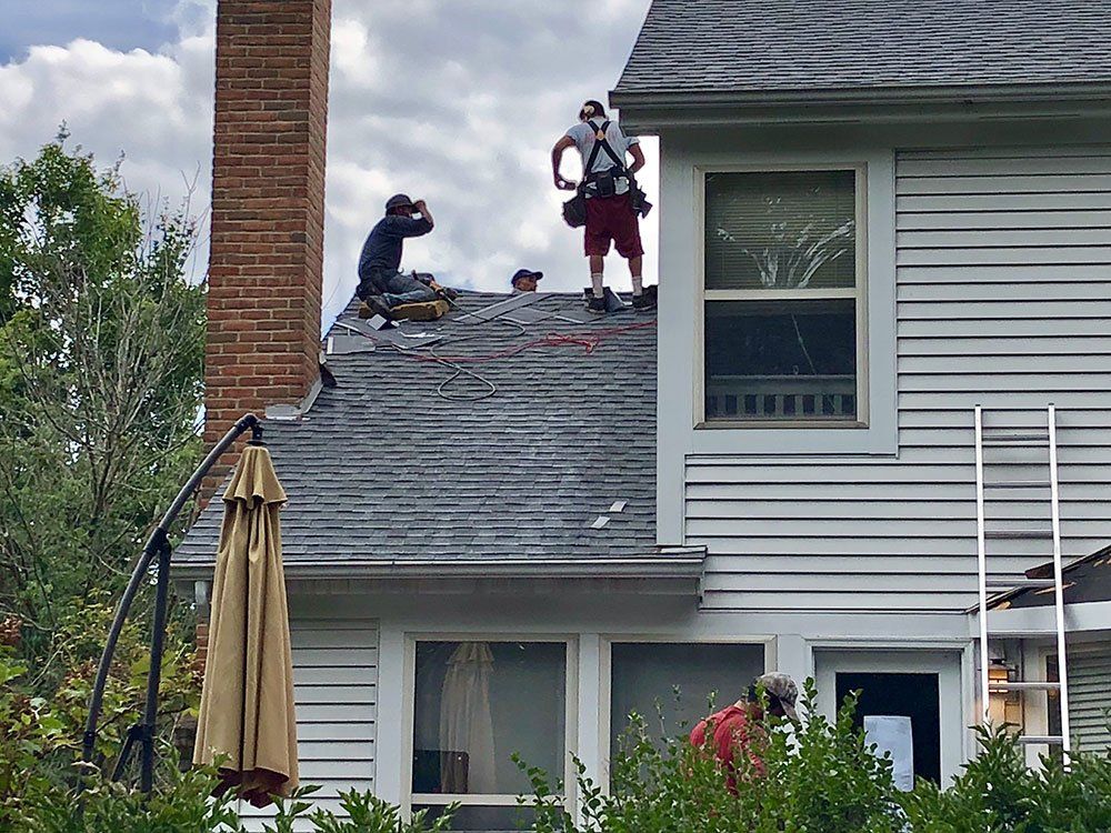 Two men are working on the roof of a house.