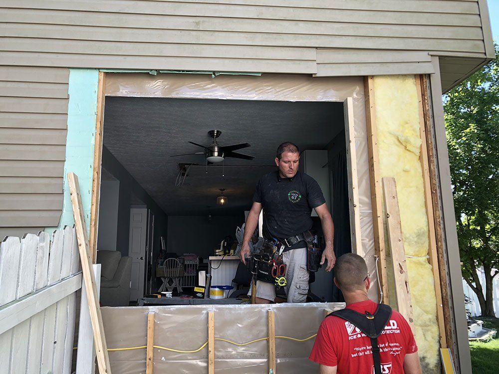Two men are working on a window in a house.