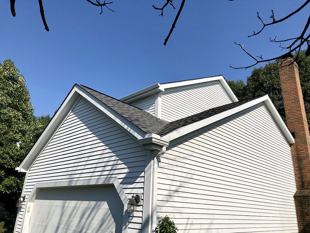 A white house with a garage and a chimney on top of it.